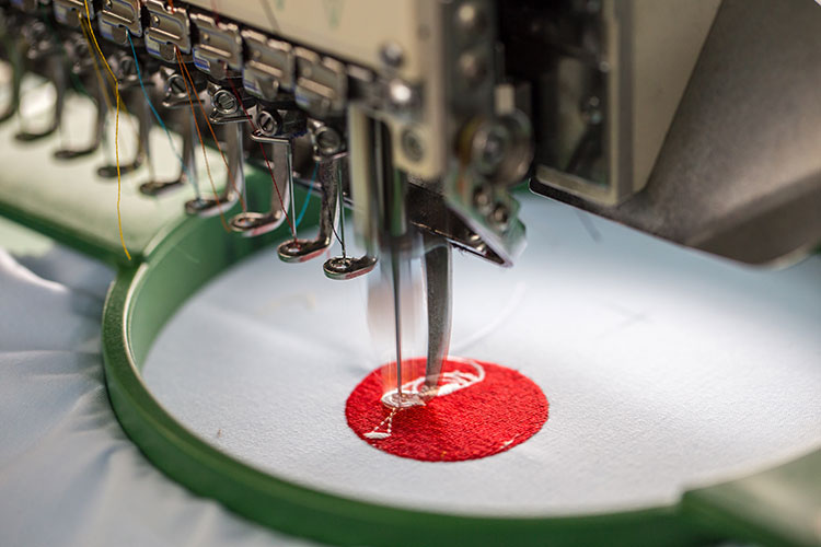 An embroidery machine head stitching a design into fabric